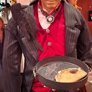  man in a suit holding a pan with a slice of pizza in it