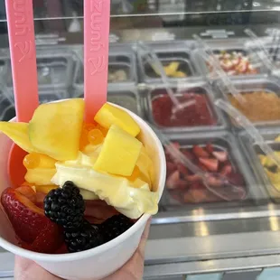 a hand holding a bowl of fruit
