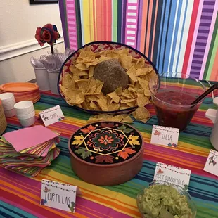 a mexican themed table with chips and guacamole