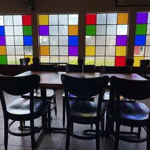 a table and chairs in front of stained glass windows