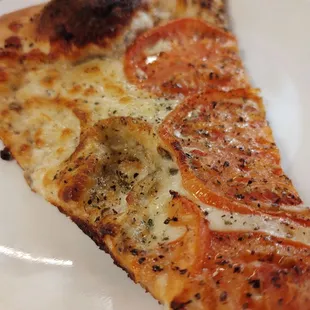 White pizza slice as it comes, with tomatoes and seasoning.