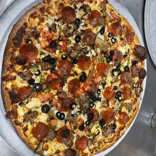 a pizza with pepperoni, sausage, and olives