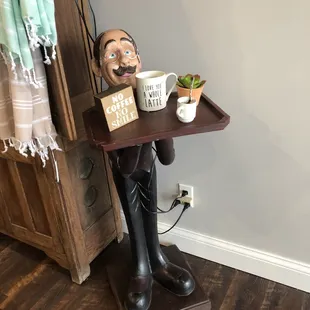 a statue of a man holding a tray of coffee