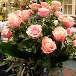 A gorgeous dozen of our signature  roses with euc in a tall sleek vase.