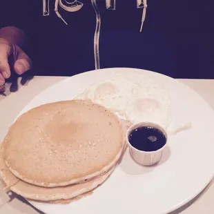 a plate of pancakes, eggs, and syrup