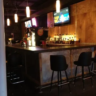 a bar with stools and a television