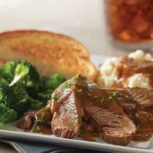 Pot Roast Homestyle Dinner, with our braised beef served with mashed potatoes, gravy, + choice of side and a buttery slice of Texas toast