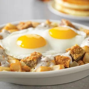 Chicken-Fried Steak Breakfast Skillet, country potatoes topped with 2 eggs and chicken-fried steak and onions in our country sausage gravy