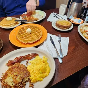 a breakfast of waffles, eggs, hash browns and bacon