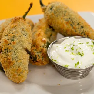 a plate of fried jalapenos with sour cream