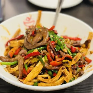 a bowl of noodles with mushrooms and peppers