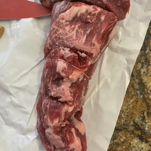 a piece of meat on a piece of paper with a knife