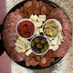 a platter of meat, cheese, and olives