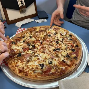 two people cutting a pizza