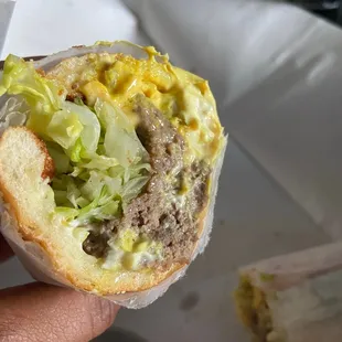 a hand holding a half eaten sandwich