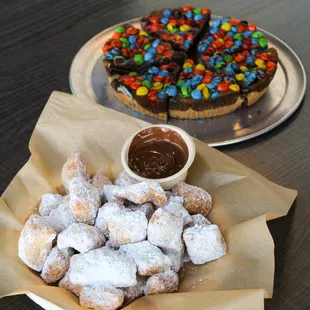 a plate of powdered sugared donuts and a chocolate covered dessert