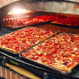 two pizzas cooking in a brick oven