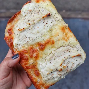 a hand holding a piece of pizza