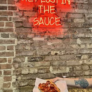 a hand holding a slice of pizza