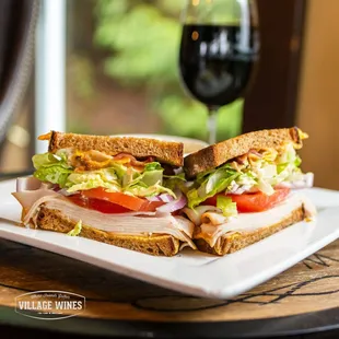 a club sandwich on a plate with a glass of wine