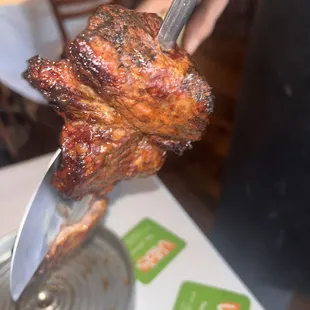 a hand holding a fork with a piece of meat on it