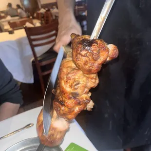 a person holding a skewer of meat