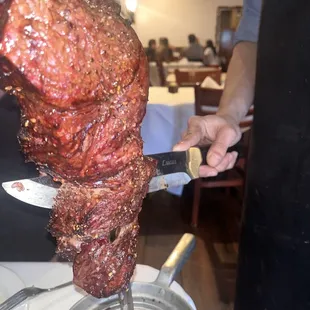 a person cutting meat on a skewer