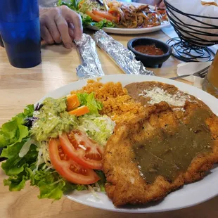 Chicken Milanesa served with rice, beans &amp; a fresh, crisp salad.