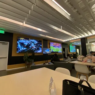 a large room with tables, chairs, and televisions