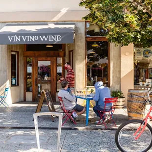 two people sitting outside a wine shop