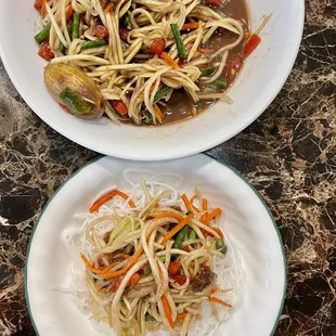 two plates of noodles and vegetables