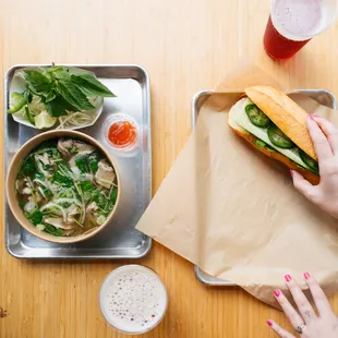 a person holding a sandwich and a bowl of soup