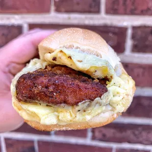 a hand holding a sausage and egg sandwich