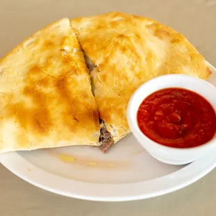 two quesadillas on a plate with a small bowl of ketchup
