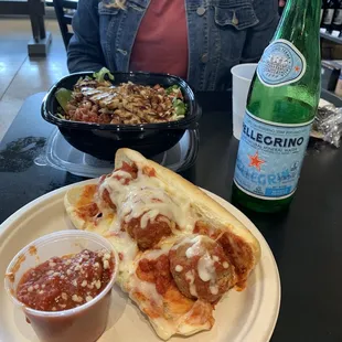a woman sitting at a table with a plate of pizza and a salad