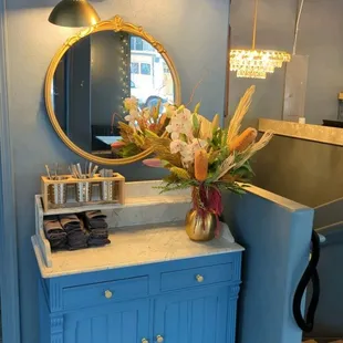 a blue vanity with a gold mirror
