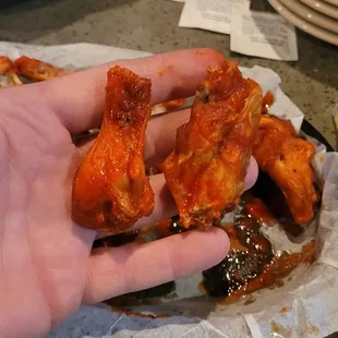 a hand holding a piece of chicken wings