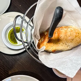 a basket of bread and a bowl of dipping sauce