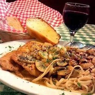 a plate of chicken, pasta, and a glass of wine
