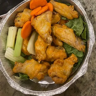 a bowl of chicken wings, carrots, celery, and celery