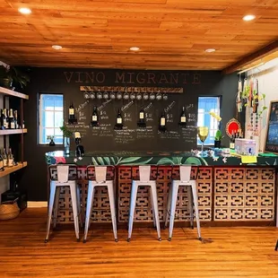 a bar with stools and bottles of wine