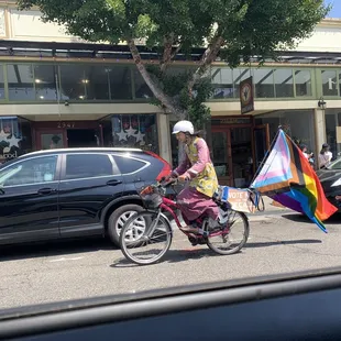 a woman on a bicycle with a rainbow flag