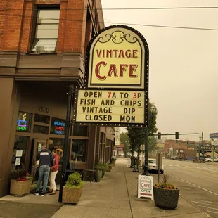 people standing on the sidewalk in front of the cafe