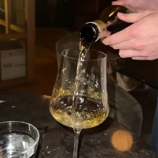 a person pouring a glass of wine
