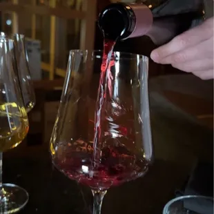 a person pouring a glass of wine