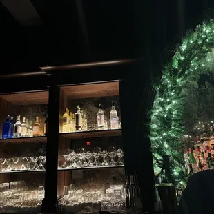 a lighted shelf of liquor bottles and glasses