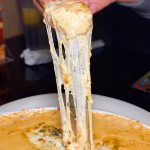 a person dipping cheese into a bowl