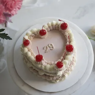 a heart shaped cake with cherries on top