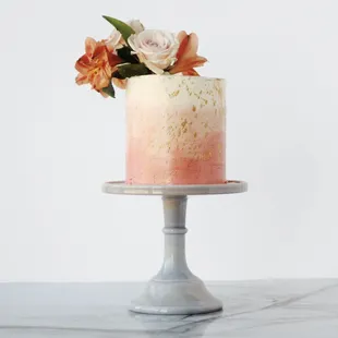 A coral pink gradient, flecked with gold, and topped with fresh Roses and Peruvian Lillies.