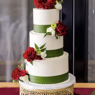 a three tiered cake with red and white flowers